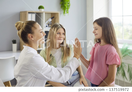 Pediatrician high fives child during clinic visit as mother watches building trust Pediatrician high fives child during clinic visit as mother watches building trust 137519972
