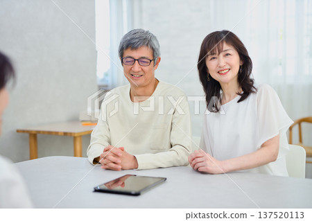 一位女銷售員正在向一對夫婦講解如何使用平板電腦 一位女銷售員正在向一對夫婦講解如何使用平板電腦 137520113