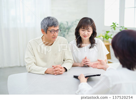 一位女銷售員正在向一對夫婦講解如何使用平板電腦 137520254