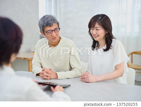 A saleswoman explaining to a couple using a tablet A saleswoman explaining to a couple using a tablet 137520255