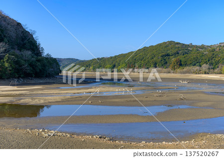 Under the blue sky, the lakebed dried up due to lack of rain and the calm lake surface 137520267