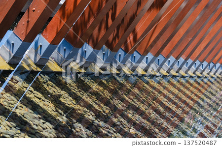 A modern waterscape featuring a reddish-brown metal grid and pebbles. 137520487