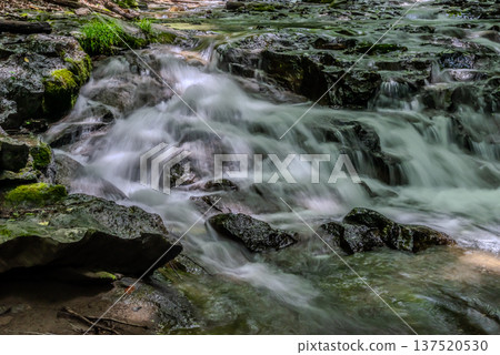 A clear stream flowing violently through rocky areas f 137520530