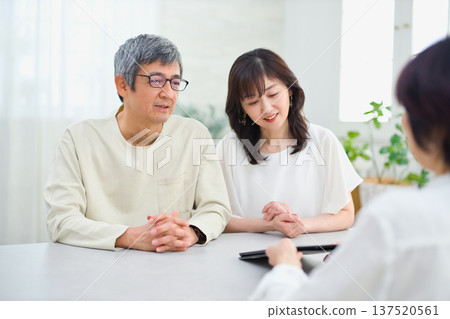A saleswoman explaining to a couple using a tablet A saleswoman explaining to a couple using a tablet 137520561
