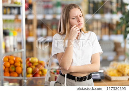 Female shopper has difficulty remembering what to buy at grocery supermarket Female shopper has difficulty remembering what to buy at grocery supermarket 137520893