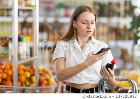 Female shopper scanning QR code on bottle soy sauce label in grocery supermarket 137520918