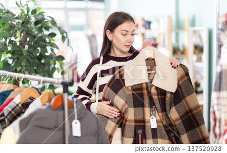 Young woman chooses jacket in clothing store 137520928