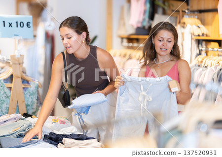 Customers stand near the shelves and choose pants Customers stand near the shelves and choose pants 137520931