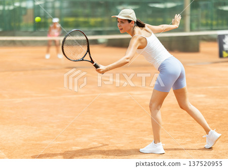 Woman playing tennis against female opponent on tennis court 137520955