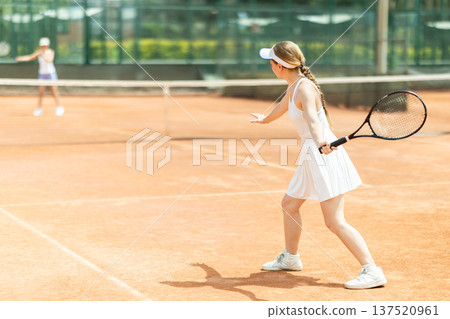 Concentrated sporty girl with tennis racquet and ball in her hands standing and ready to play match standing 137520961