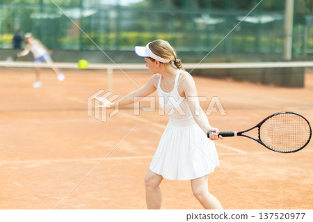 Female athlete plays tennis on open court Female athlete plays tennis on open court 137520977