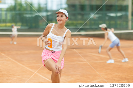 On tennis court, girl applies sunscreen to body 137520999