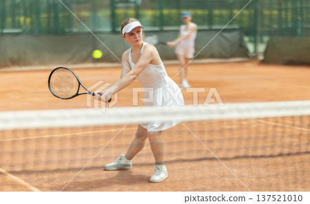 Female athlete plays tennis on open court Female athlete plays tennis on open court 137521010