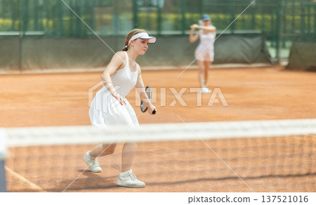 Woman playing tennis against female opponent on tennis court 137521016