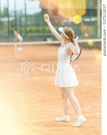 Woman playing tennis against female opponent on tennis court 137521017