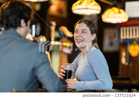 Young woman drinking beer and chatting with man at bar Young woman drinking beer and chatting with man at bar 137521024