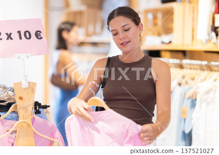 Young woman choosing a blouse in a store Young woman choosing a blouse in a store 137521027
