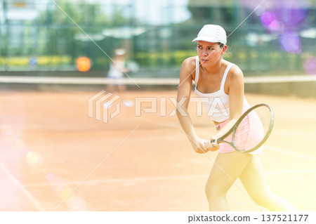 Female athlete plays tennis on open court Female athlete plays tennis on open court 137521177