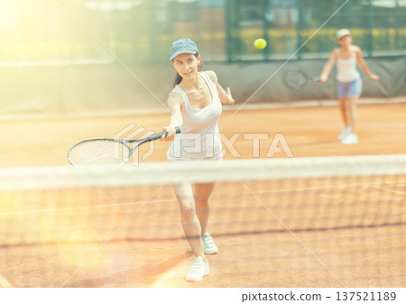 Female athlete plays tennis on open court 137521189