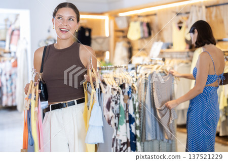 Two women standing in a boutique and choosing clothes Two women standing in a boutique and choosing clothes 137521229