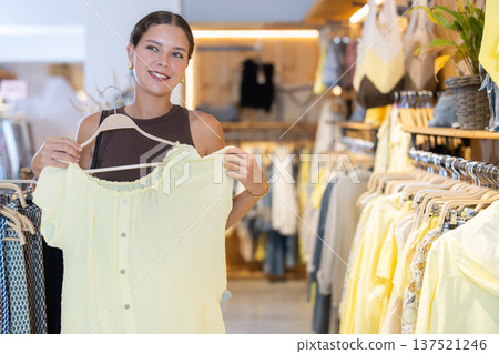 Young woman choosing blouse in clothing store 137521246