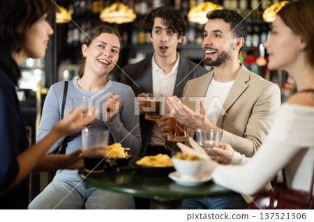 Group of happy friends spending time in bar, having fun while drinking beer and talking Group of happy friends spending time in bar, having fun while drinking beer and talking 137521306