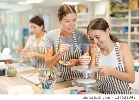 Female teacher explains to student how to paint ceramics 137521342