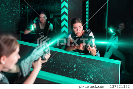 Girls play laser tag, jokingly fight with light weapons Girls play laser tag, jokingly fight with light weapons 137521352
