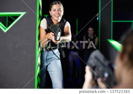 Team of young girlfriends play laser tag in labyrinth. Girls spend time actively 137521383