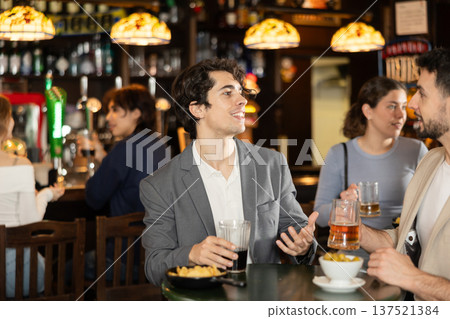 Young men sitting in bar drinking beer Young men sitting in bar drinking beer 137521384