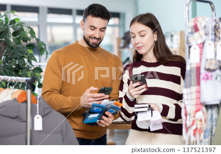 Couple scans QR code and label of socks in shop Couple scans QR code and label of socks in shop 137521397