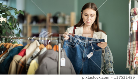 Young woman choosing jeans pantaloons in clothing store Young woman choosing jeans pantaloons in clothing store 137521489