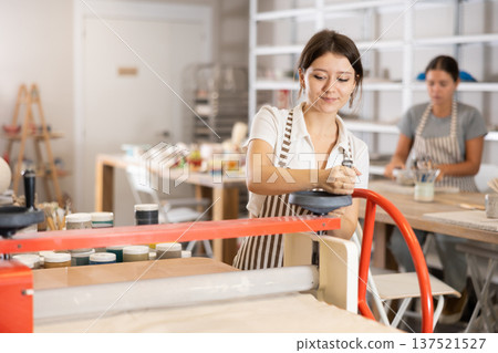 Young girl working on polymer clay rolling machine Young girl working on polymer clay rolling machine 137521527