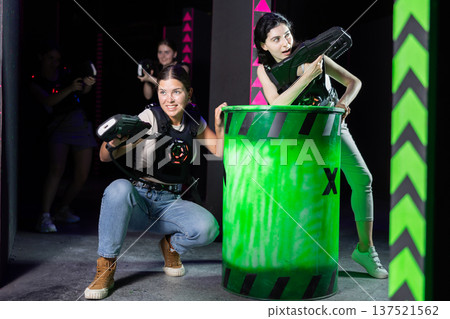 Girls play laser tag, jokingly fight with light weapons Girls play laser tag, jokingly fight with light weapons 137521562