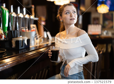 Portrait of an attractive woman with glass of cocktail at bar counter Portrait of an attractive woman with glass of cocktail at bar counter 137521579