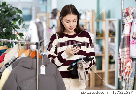 Young woman scans qr code of gloves in store 137521587