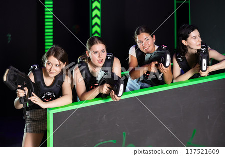 Girls play laser tag, jokingly fight with light weapons Girls play laser tag, jokingly fight with light weapons 137521609