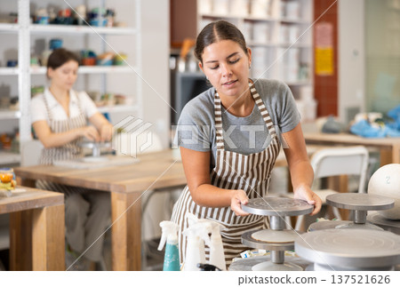 Young woman puts pottery wheel for making ceramics Young woman puts pottery wheel for making ceramics 137521626