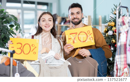 Happy couple, woman and man holding sign saying Sale for winter season standing in interior of clothing boutique 137521677