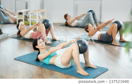 Young girls doing press with softball band between legs lying on the floor 137521690