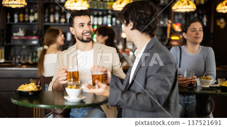 Two men discuss news and business over glass of beer in bar Two men discuss news and business over glass of beer in bar 137521691