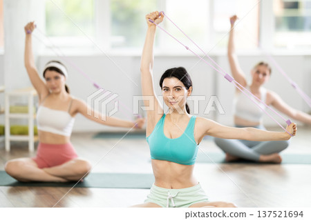 Group of young women doing pilates with loop Group of young women doing pilates with loop 137521694