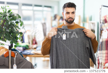 Young man choosing sweater in clothing store Young man choosing sweater in clothing store 137521776