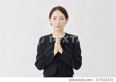 Woman in mourning clothes, hands together, white background, looking at camera 137521872