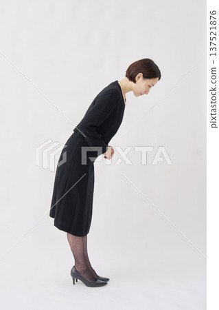 身著喪服的女子鞠躬，白色背景，全身照，面向右側。 137521876