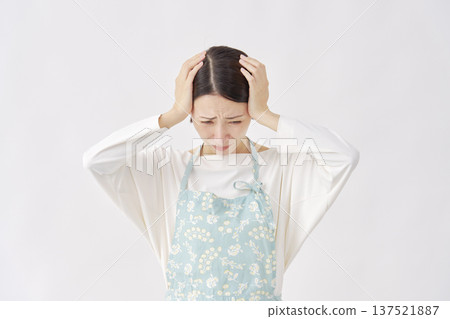 Woman wearing an apron holding her head, white background Woman wearing an apron holding her head, white background 137521887