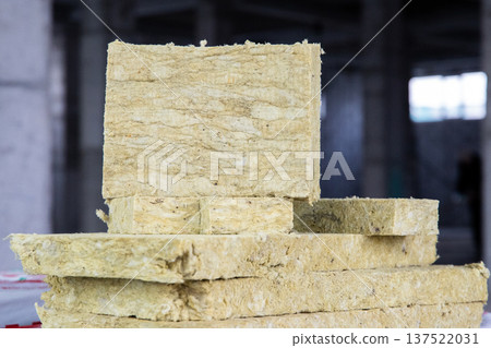 Professional rock wool insulation slabs stacked on a construction site, ready for wall or roof installation. Professional rock wool insulation slabs stacked on a construction site, ready for wall or roof installation. 137522031