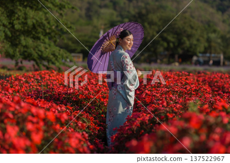 woman in yukata (kimono dress) holding umbrella with flower blooming in garden woman in yukata (kimono dress) holding umbrella with flower blooming in garden 137522967
