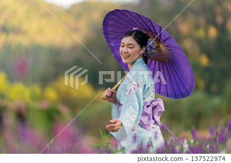 woman in yukata (kimono dress) holding umbrella with angelonia flower blooming in garden 137522974