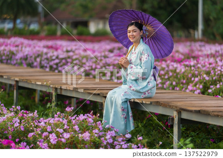 woman in yukata (kimono dress) holding umbrella with flower blooming in garden woman in yukata (kimono dress) holding umbrella with flower blooming in garden 137522979